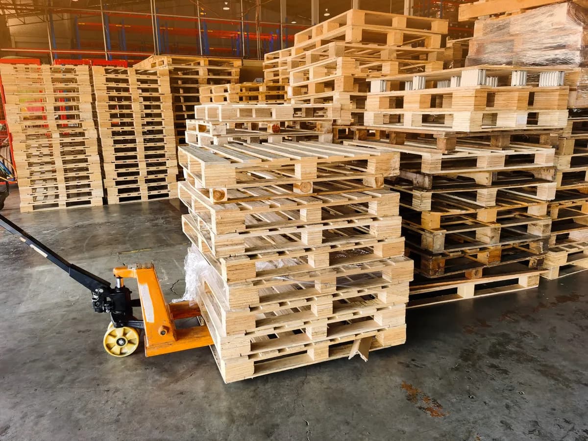Stacks of new wooden pallets with a pallet jack on a warehouse floor