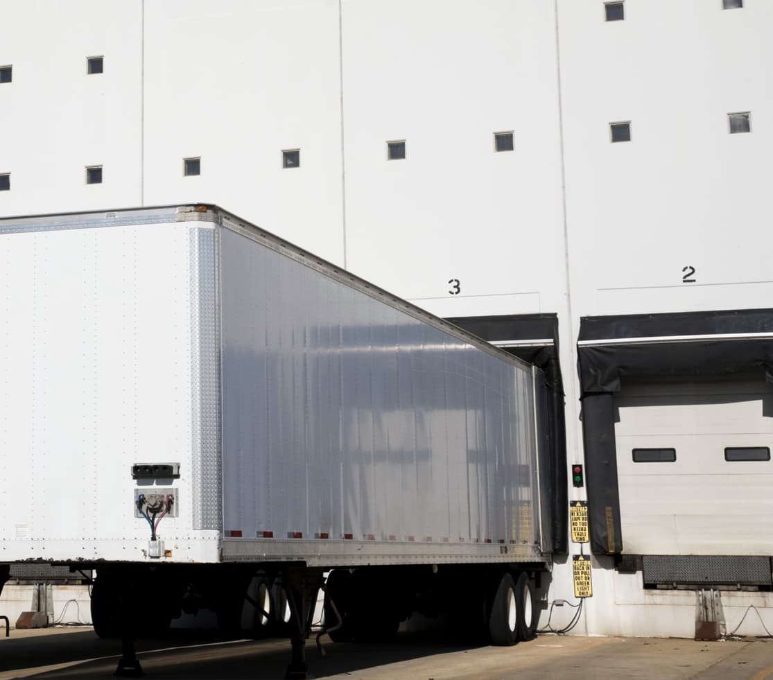Large trailer parked at warehouse loading dock for pallet drop trailer service