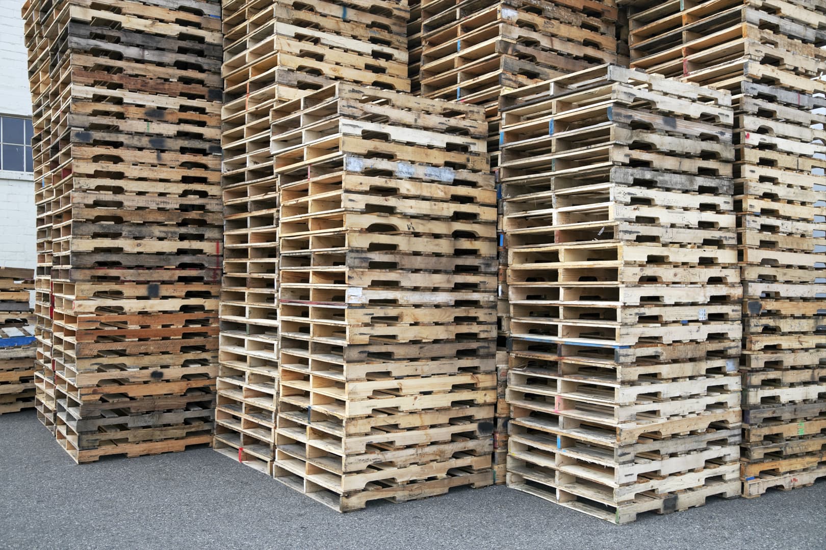Pallet yard with 48x40 wood pallets stacked and organized for hauling, side view of pallets