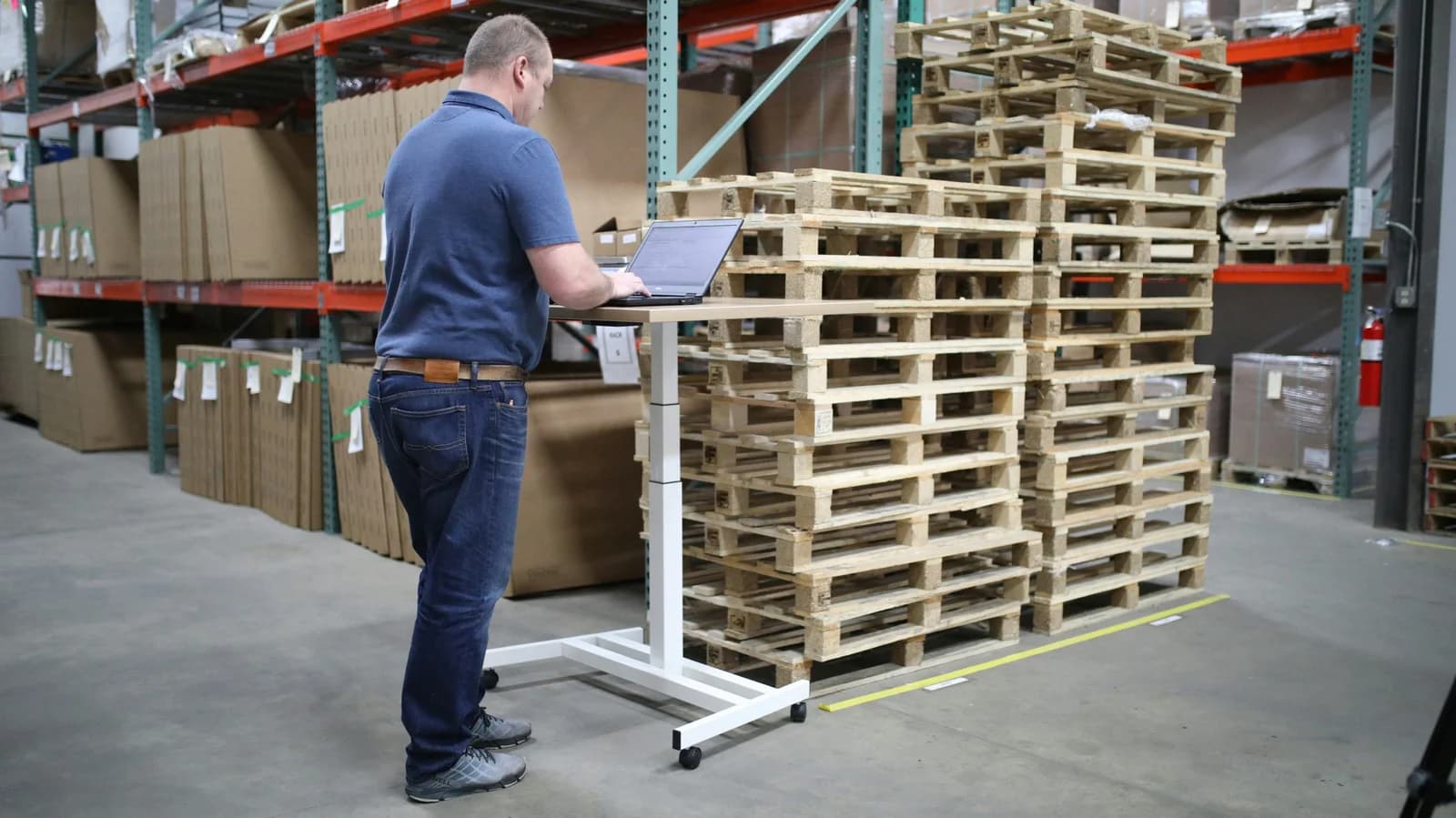 man standing at laptop in front of pallets